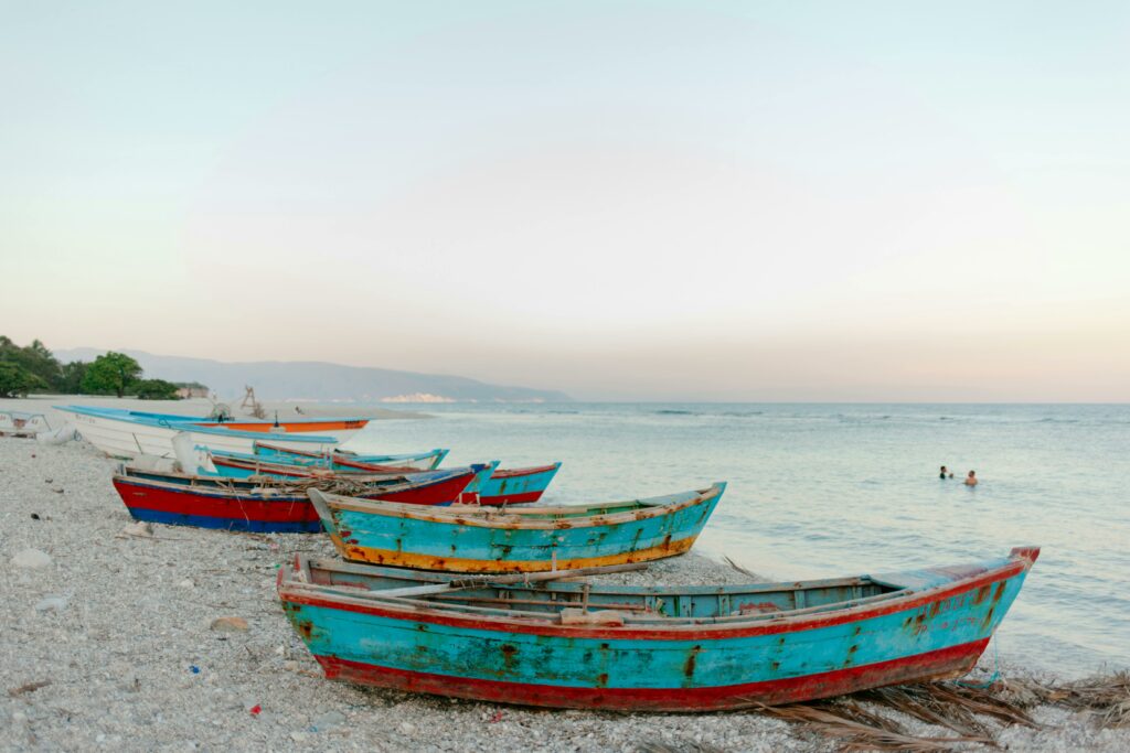 Rustic fishing boats line the peaceful shoreline of a Dominican Republic beach at sunset, offering a tropical escape.