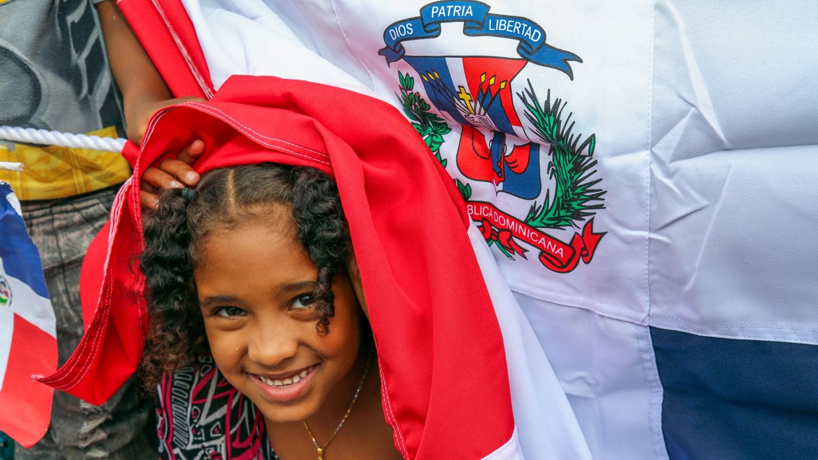 A smiling girl wrapped in the Dominican Republic flag