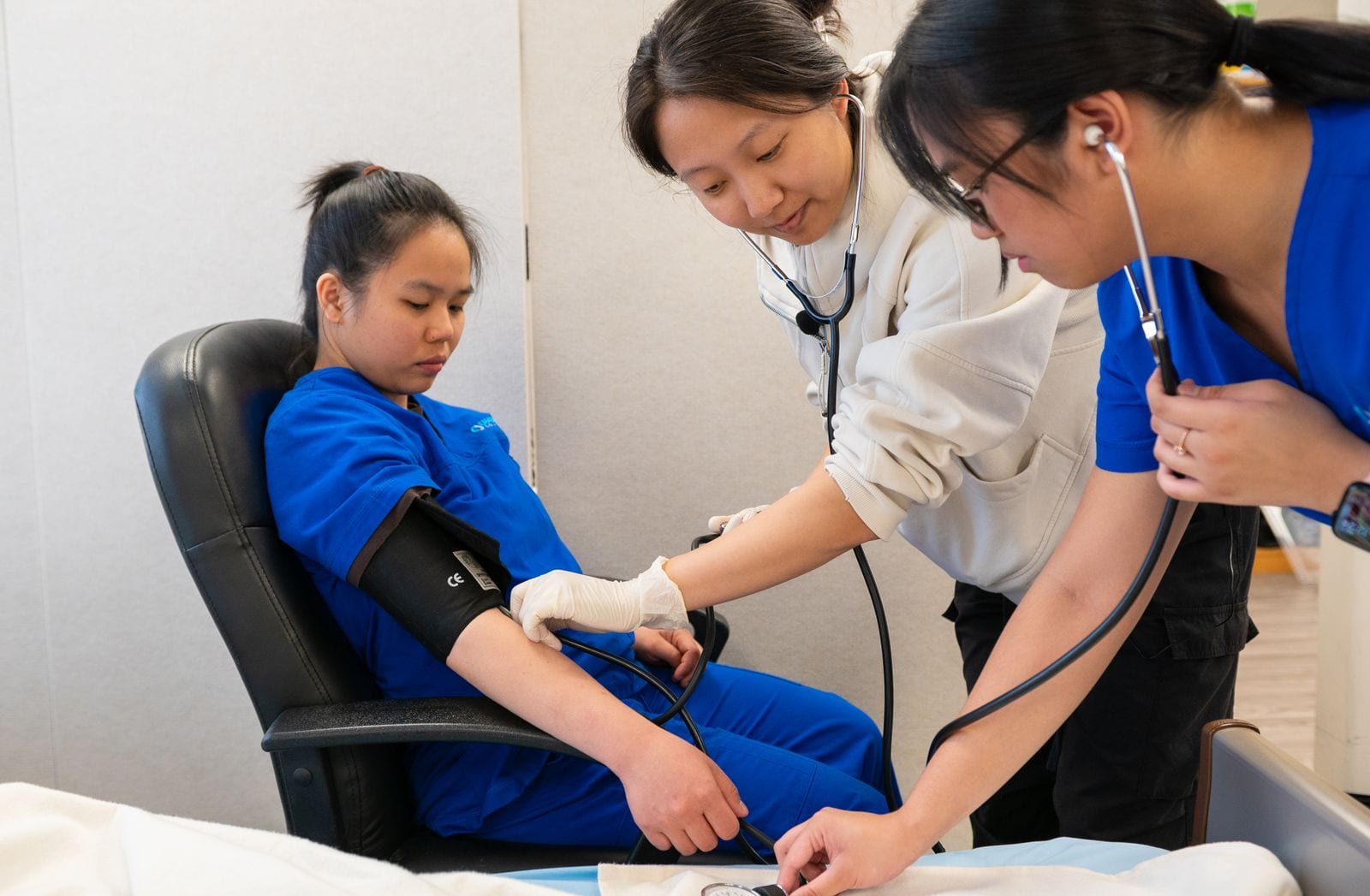 Students checking a patient's blood pressure in a clinic